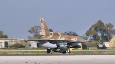 F-16 askeri jet uçağı kanatlarının altında yakıt tanklarıyla uçuyor.