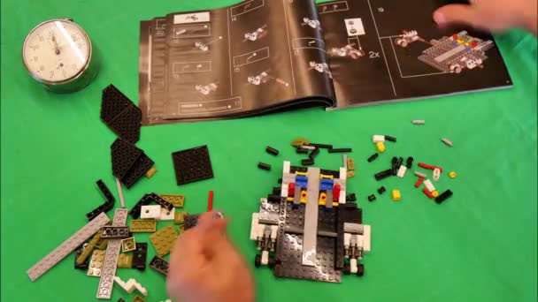 Stop met bewegen, Close-up van handen die LEGO blokken assembleren in 10283 NASA Space Shuttle Discovery. — Stockvideo
