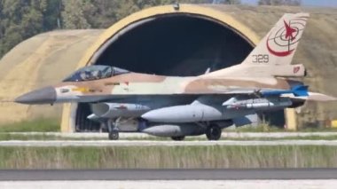 Fighter jet armed with missiles and external fuel tanks taxiing in an airport