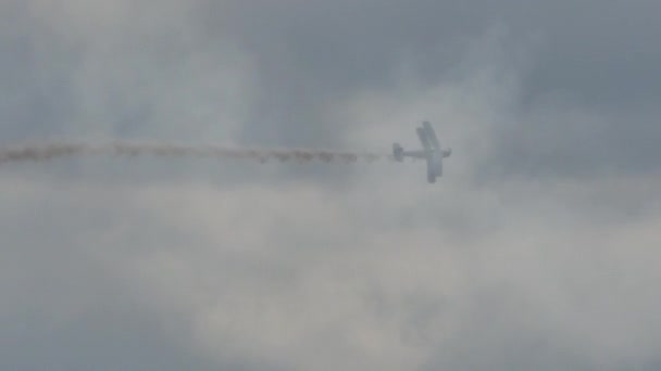 Vintage biplane made voltige harmonious maneuvers highlighted by the smoke — Stock Video
