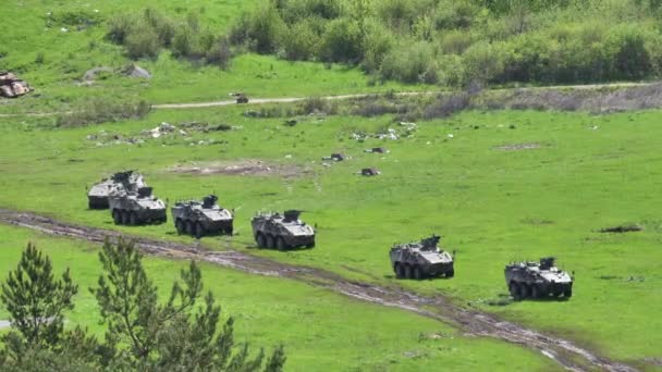 Yeşil tarlalardaki çamurlu yolun yakınına park edilmiş zırhlı araçlar. Askeri tatbikat — Stok video