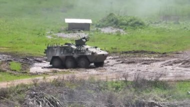 Hafif tekerlekli zırhlı araç çamurlu arazide sürüyor. Atış menzili 