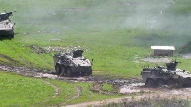 Tekerlekli zırhlı taşıma araçlarının tozlu arazide sergilendiği askeri sergi