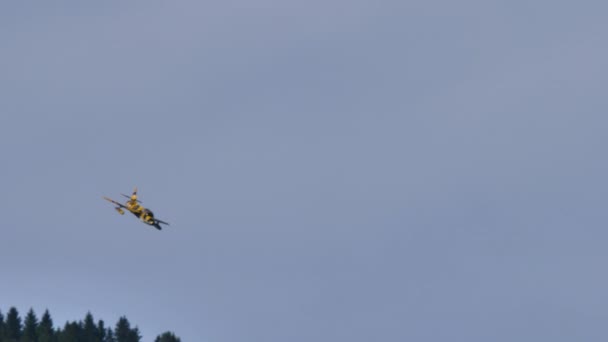 Történelmi katonai repülőgép alacsonyan repül a kék ég és a zöld alpesi völgyek között. — Stock videók