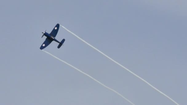 Kék propeller vadászgép repülő repülés fehér nyomvonal a szárny hegyén — Stock videók