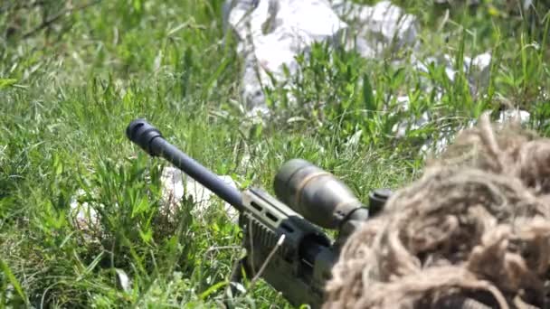 Disparando con francotirador bajo camuflaje. Soldado irreconocible tirado en el suelo — Vídeos de Stock