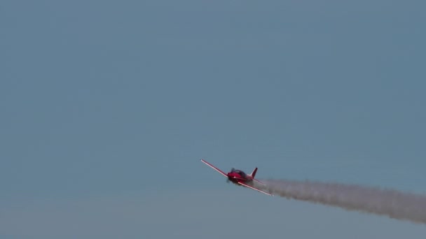 Pesawat baling-baling merah kecil terbang di langit biru dengan jejak asap putih — Stok Video