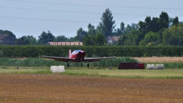 Small red propeller vintage plane takes off from grass strip aerodrome — Stock Video