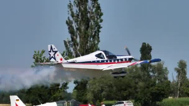Маленький белый самолет с красно-синим флагом США окрашен взлетает с дымом — стоковое видео