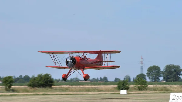 Biplano vermelho histórico em voo a baixa altitude sobre um campo no campo — Fotografia de Stock