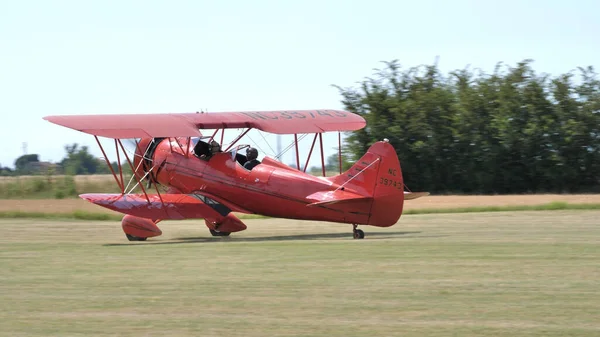 Röd vintage biplane från 1930-talet parkerad i ett gräsflygfält på landsbygden — Stockfoto