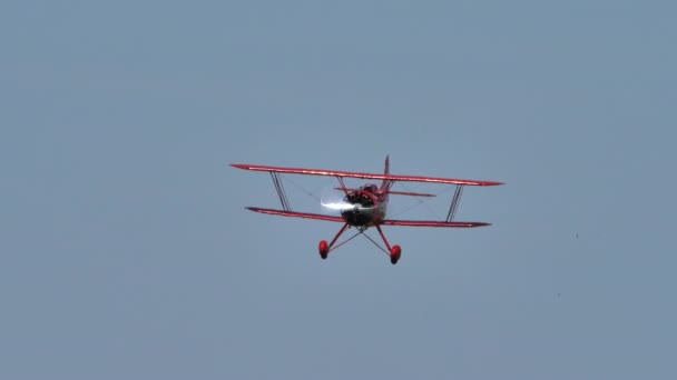 Vintage red biplane from 1930 in flight in a blue summer sky without clouds — Stock Video