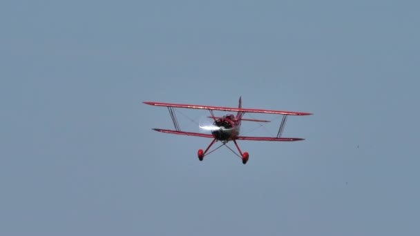 Vintage rött biplan från 1930 i flygning i en blå sommarhimmel utan moln — Stockvideo