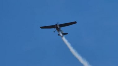 Retro askeri pervane Cessna uçağı mavi gökyüzünde dumanla yuvarlanıyor