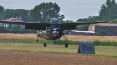 Retro yeşil pervaneli uçak ve köpek balığı ağzı çim pistine iniyor.