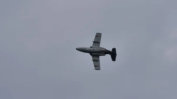 Avião militar cinzento em voo em um céu nublado — Fotografia de Stock