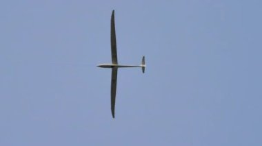 Mavi yaz gökyüzünde uzun kanatlarıyla uçan planör.