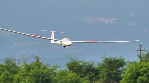 Avión de vela aterrizando con los alerones abiertos en un aeródromo de hierba verde — Vídeos de Stock