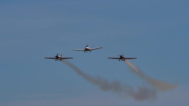 青い空に白い煙と共に形成された低速度で飛行する軽飛行機 — ストック動画