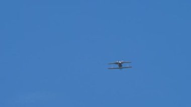 Aerobatik klasik çift kanatlı uçak bulutsuz mavi gökyüzünde yuvarlanıyor.