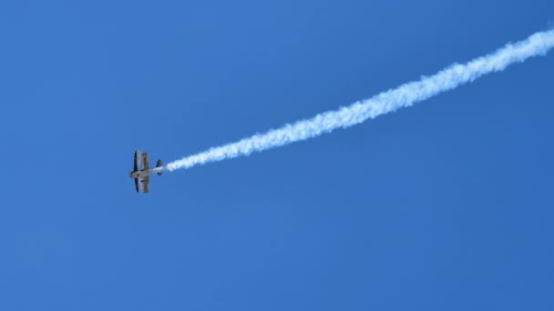 4k video de un avión biplano retro volando en el cielo azul con rastro de humo blanco — Vídeos de Stock