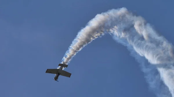 Figura acrobática dibujada en el cielo por la estela blanca de un pequeño avión de hélice —  Fotos de Stock