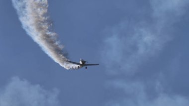 Mavi yaz gökyüzünde uçmakta olan beyaz patikalı bir uçak.