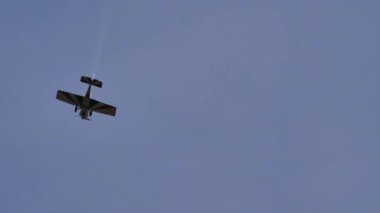 Mavi gökyüzünde küçük bir uçağın beyaz duman izleriyle muhteşem uçuş numaraları.