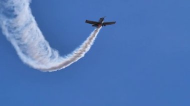 Yoğun mavi gökyüzünde yuvarlanan bir uçak tarafından yapılan beyaz duman izi.