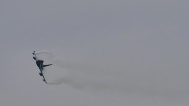 Gri gökyüzünde uçmakta olan beyaz kuyruklu uçak yüksek performans dönüşü yapar