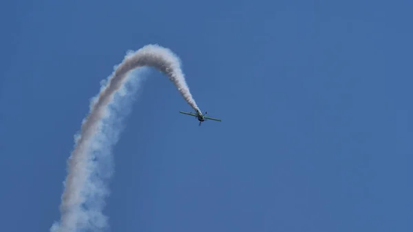 Aşırı akrobatik uçak mavi gökyüzünde beyaz duman iziyle uçuyor. — Stok fotoğraf