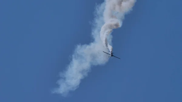 Avion acrobatique dans le ciel bleu avec une fumée blanche. Espace de copie. — Photo