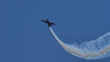 Aerobatik uçak, beyaz dumanla dikey olarak mavi gökyüzüne yükselir.