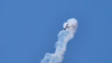 Mavi gökyüzünde dumanlı bir akrobatik uçak tarafından yüksek hızda yuvarlanmalar.