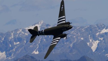 Appenzell İsviçre 30 Mayıs 2025: Müttefik savaş kuşu hatıra uçuşları, bir hava gösterisi sırasında parlak bir gökyüzü altında muazzam karlı dağ zirvelerini geçer. Douglas C-47 Skytrain. Boşluğu Kopyala