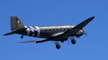 APPENZELL, SWitzERLAND - 30 Mayıs 2025: klasik C-47 Skytrain askeri nakliye aracı mavi gökyüzüne karşı uçuyor. Douglas nakliye uçakları D-Day istila çizgileri takıyor. Boşluğu Kopyala