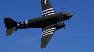 ApPPENZELL, SWitzERLAND - 30 Mayıs 2025: C-47 Skytrain asker taşıyıcı bankacılık bel altı ve işgal çizgileri görünür bir dönüş sırasında. Douglas askeri nakliye uçağı havada. Boşluğu Kopyala