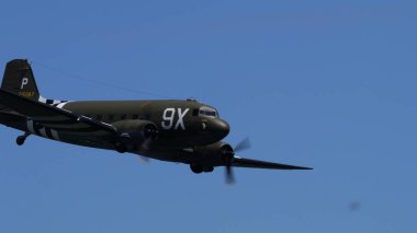 31 Mayıs 2025 'te Douglas C-47 Skytrain kokpitini ve uçuş halindeki burnunu kapatın. Tarihi 2. Dünya Savaşı uçağı 101. Hava indirme işareti ve negatif uzay.