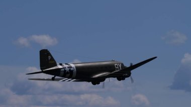 APPENZELL, SWitzERLAND - 31 Mayıs 2025: Tarihsel Douglas C-47 Skytrain mavi bir ufuk çizgisinde bankacılık yapıyor. İşgal çizgileri ve kopyalama alanı olan 2. Dünya Savaşı nakliye uçağı.