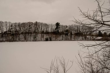 Dorchester, Kanada 'daki donmuş gölette buz pateni pistini temizlemiş. Buz hokeyi sahasında donmuş su üzerinde beyaz kar hareket etti. Donmuş gölde kırmızı buzda balık tutma çadırı