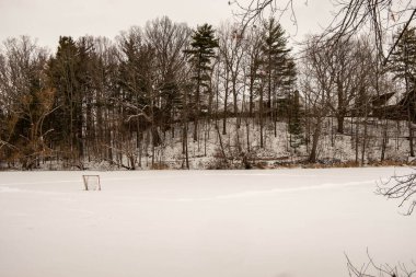 Dorchester, Kanada 'daki donmuş gölette buz pateni pistini temizlemiş. Buz hokeyi sahasında donmuş su üzerinde beyaz kar hareket etti. Donmuş gölde kırmızı buzda balık tutma çadırı