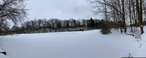Dorchester, Kanada 'daki donmuş gölette buz pateni pistini temizlemiş. Buz hokeyi sahasında donmuş su üzerinde beyaz kar hareket etti. Donmuş gölde kırmızı buzda balık tutma çadırı