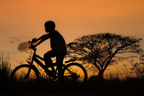 Silhueta de crianças e bicicleta em pôr-do-sol — Fotografia de Stock