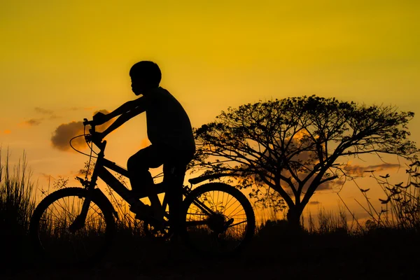 Silhueta de crianças e bicicleta em pôr-do-sol — Fotografia de Stock