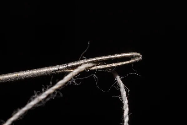 Enter the thread through the needle on a black background isolat — Stock Photo, Image