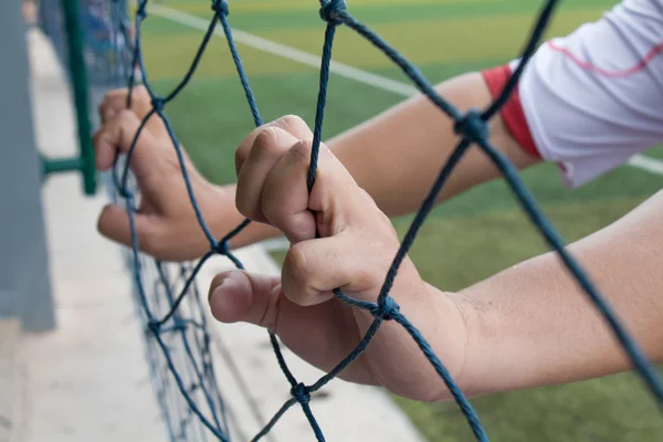 Mano sosteniendo la red de fútbol al lado de un estadio de fútbol —  Fotos de Stock