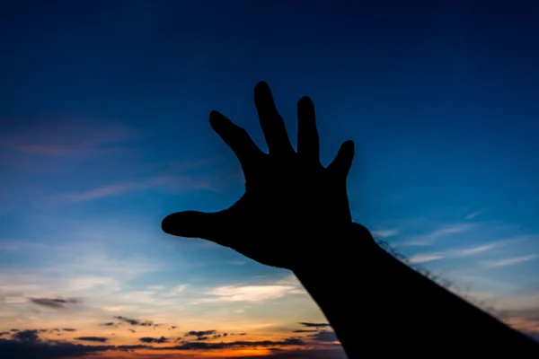 Mano tratar de llegar a algo silueta en el cielo —  Fotos de Stock