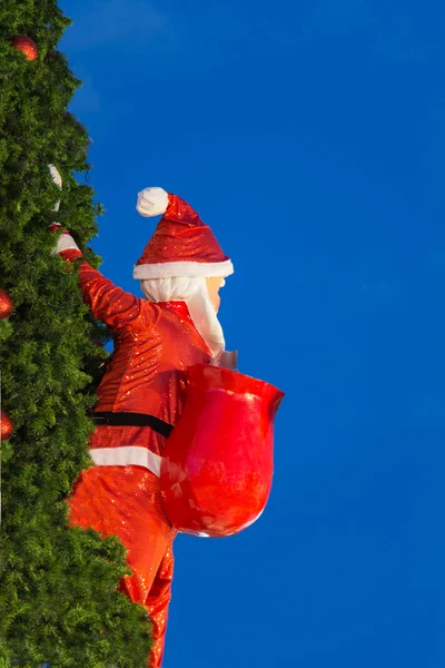 Papai Noel carregando um saco de presentes na árvore de Natal . — Fotografia de Stock