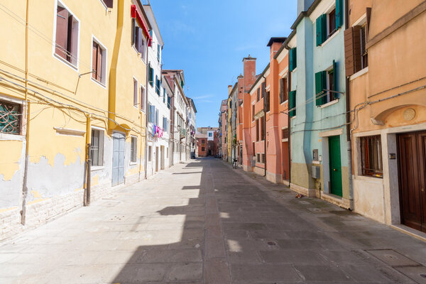 Street feature with multicolored houses in Chioggia, the little Venice, on a summer day