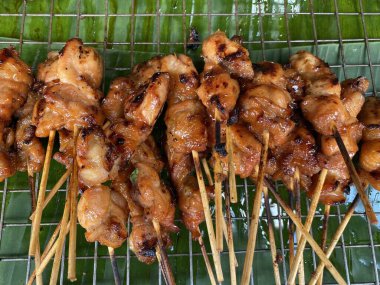 Markette satılık yeşil muz yaprağında ızgara tavuk şişleri.